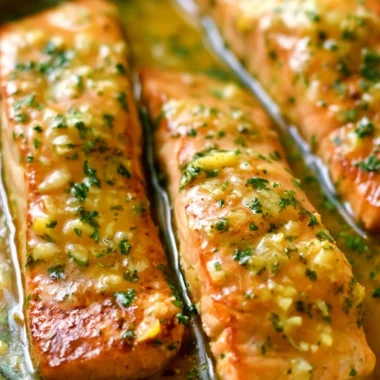 Delicious Garlic Butter Salmon served with herbs and lemon on a plate.