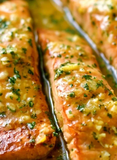 Delicious Garlic Butter Salmon served with herbs and lemon on a plate.