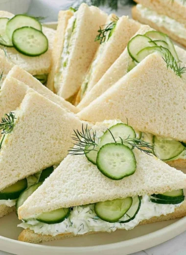 Plate of fresh cucumber sandwiches served with tuna and tomato slices.