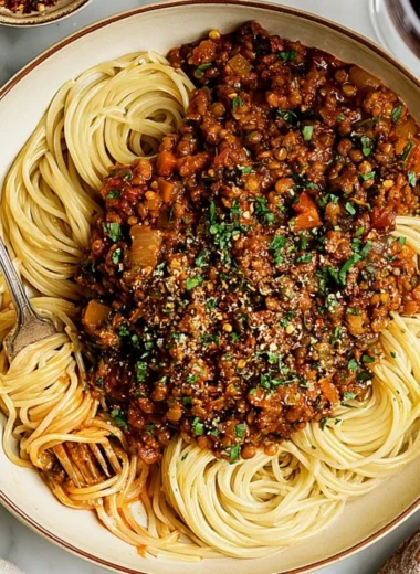 Delicious vegan lentil bolognese served with pasta and fresh herbs