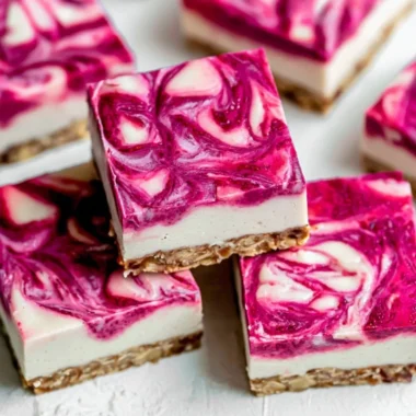 Delicious Vegan Raspberry Cheesecake Bars topped with fresh raspberries.