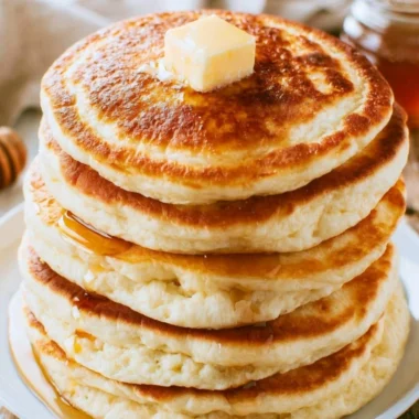 Stack of fluffy pancakes served with maple syrup and fresh berries
