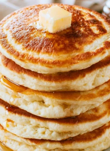 Stack of fluffy pancakes served with maple syrup and fresh berries