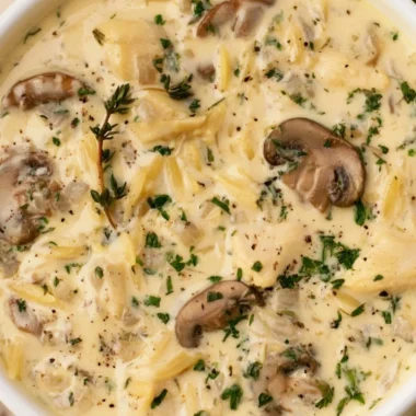 Bowl of creamy chicken soup with Boursin cheese garnished with fresh herbs.