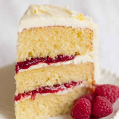 Delicious Raspberry Lemon Cake topped with fresh raspberries and lemon zest.