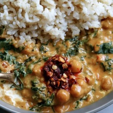 Bowl of Steph's Chickpea Curry with Spinach and Rice, garnished with fresh herbs.