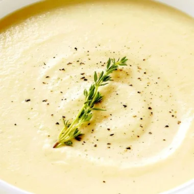 Creamy bowl of cauliflower soup topped with fresh herbs and served warm.