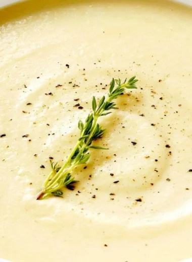 Creamy bowl of cauliflower soup topped with fresh herbs and served warm.