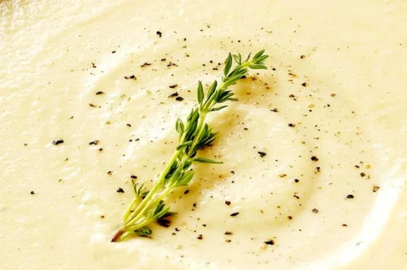 Creamy bowl of cauliflower soup topped with fresh herbs and served warm.